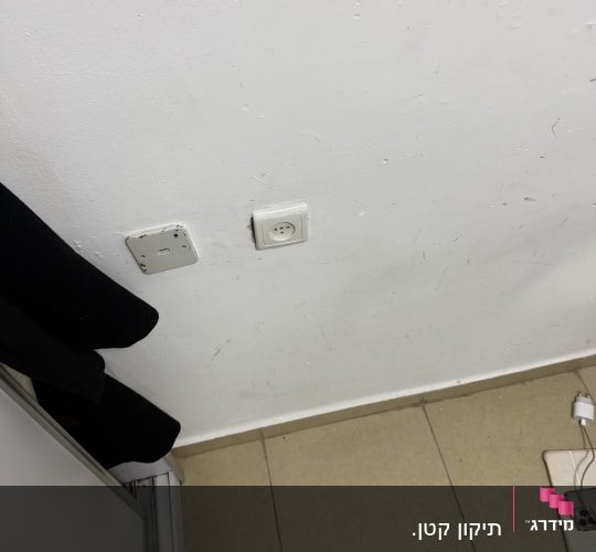 שקע חשמל על קיר לבן עם רצפת אריחים